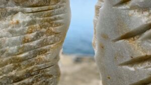 a view of a distant ocean and beach, glimpsed through a crack between two pieces of rock