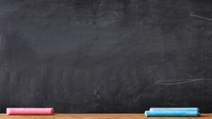 a dark grey blackboard, with one pink and blue piece of chalk on a ledge at the foot of it